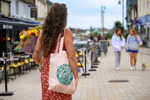Lady holding tote bag walking through town